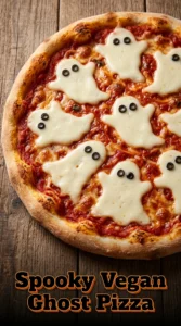 Five vegan pizzas topped with melted white vegan cheese shaped like ghosts with olive eyes and mouths on red sauce.