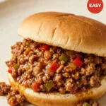 Two sloppy joe sandwiches on toasted buns with hearty ground beef filling, served on a rustic wooden board.