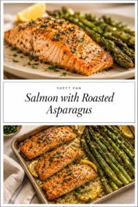 Roasted salmon fillets and green asparagus spears seasoned with lemon slices and herbs on a dark metal sheet pan.