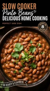A white bowl filled with slow cooked pinto beans in a savory brown broth, garnished with fresh cilantro leaves.